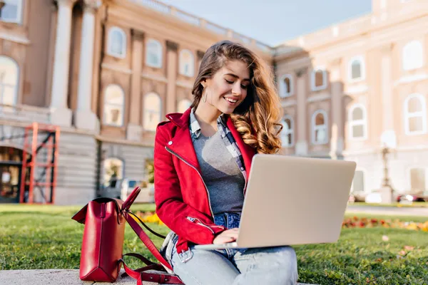 סטודנטית עם מעיל אדום לומדת במחשב הנייד